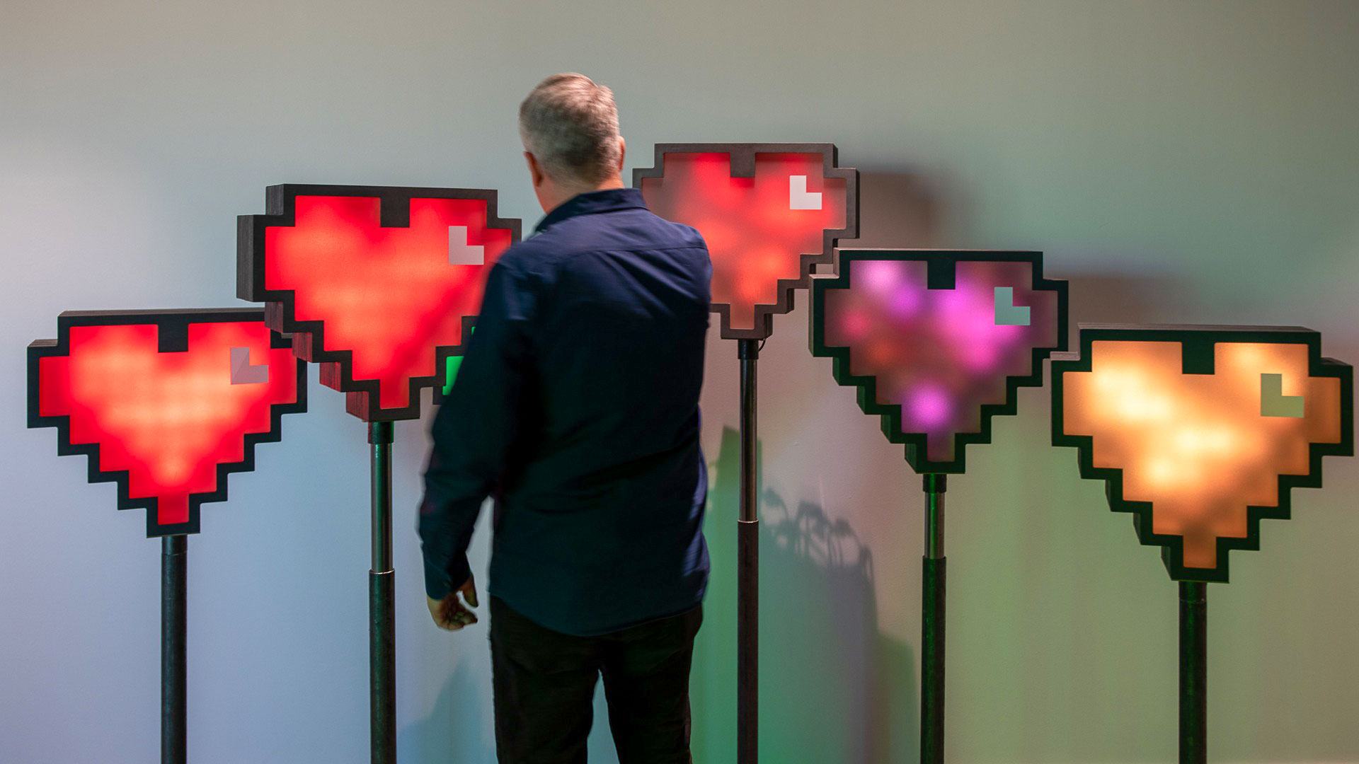 Man står vid en rad med pixelhjärtan.