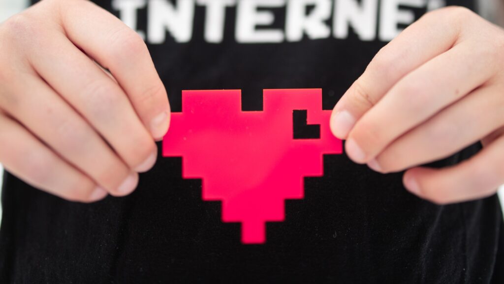 Händer håller i pixel-hjärta.
