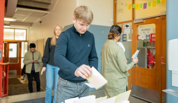 En ung kille plockar valsedlar i en vallokal.