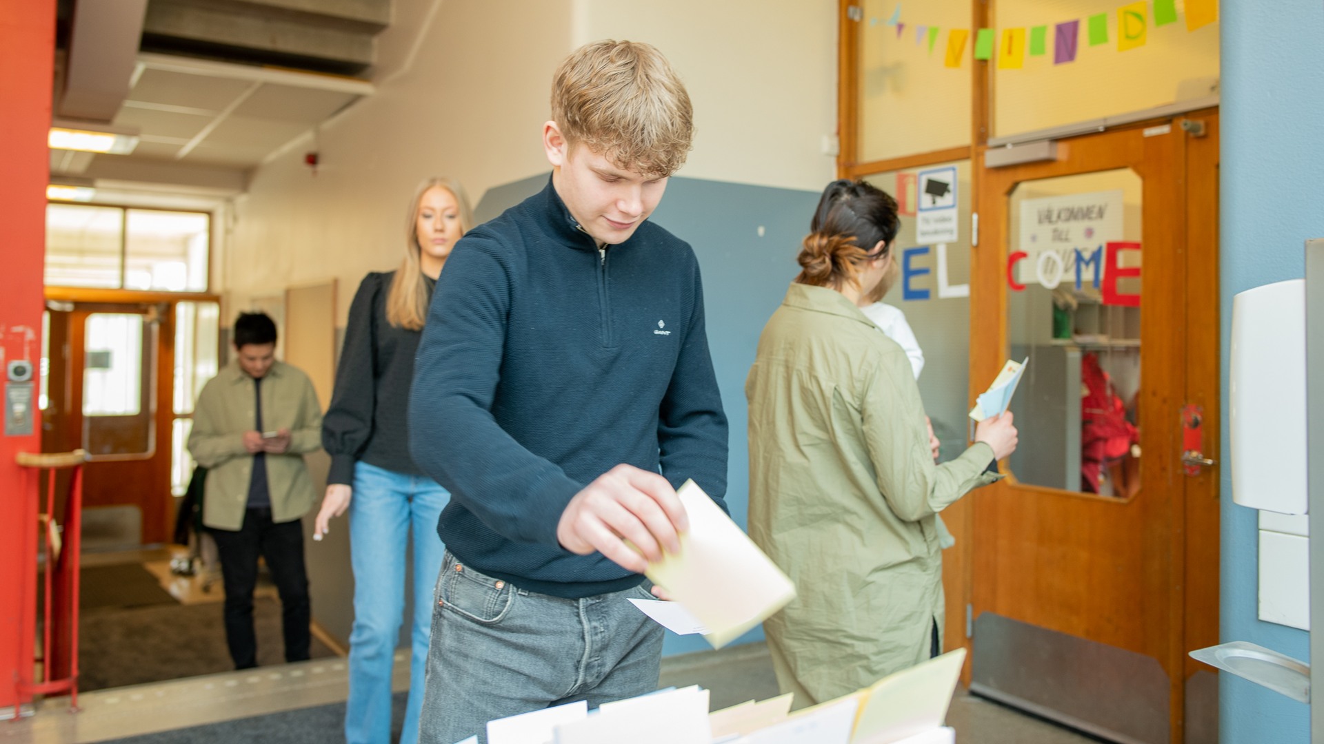 En ung kille plockar valsedlar i en vallokal.